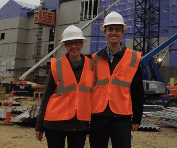 Two scholars in orange worker vests at an internship site.
