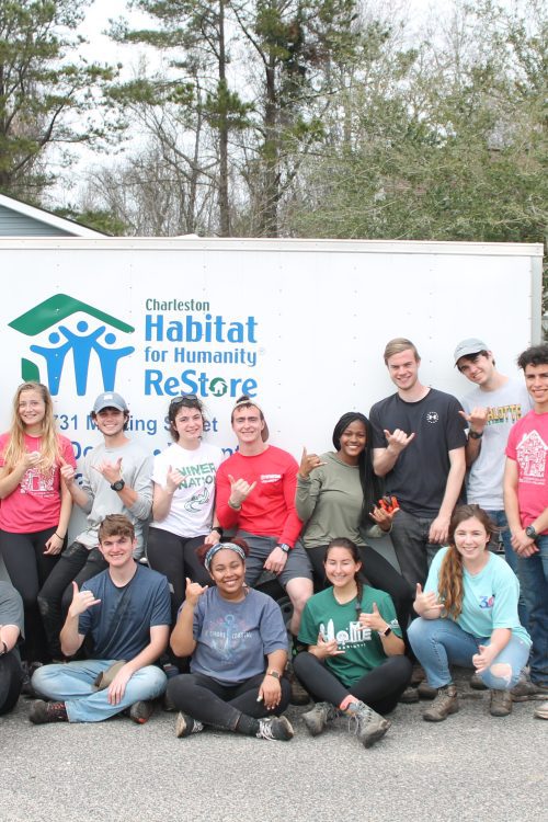A group of scholars standing in front of a Habitat for Humanity supply trailer.