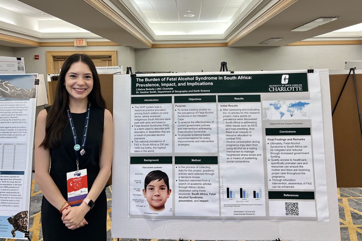 A scholar standing by her research project poster.