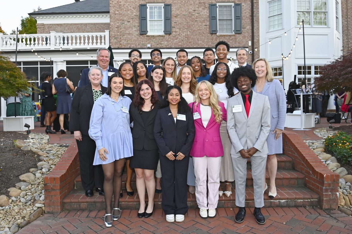 A group of students/scholars pose for a photo at the chancellor's house during an event.